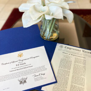 Two Congressional Awards for Ed Stacks, on a table with white flowers in a clear glass vase in the background.