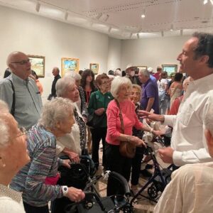 Museum gallery designer facing older adult crowd